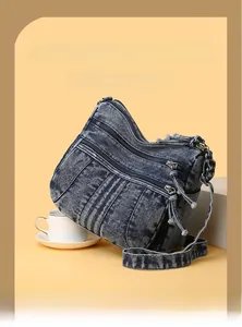 Détail d'un sac à bandoulière en denim multi-poches avec tissu délavé et fermetures éclair