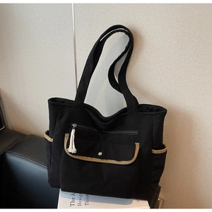 Detail of black corduroy tote bag featuring multi-pocket design and contrast trim
