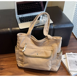 Detail of khaki corduroy tote bag with olive green pocket and metallic buckle closure