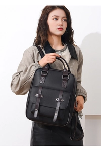 Détail d'un sac à dos vintage en cuir noir avec sangles brunes et rivets en métal
