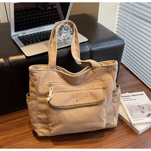 Close-up of corduroy tote bag showing functional outer pockets and premium metal button