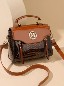 Detail of snake embossed texture and gold M logo on brown crossbody handbag