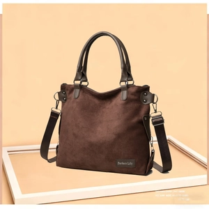 Detail view of large brown suede tote bag featuring leather handles and brand logo tag