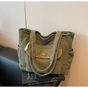 Detail of green corduroy tote bag featuring flap pocket and soft tassel zipper puller