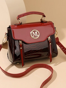 Detail of red and black snakeskin pattern handbag with golden metal M logo buckle