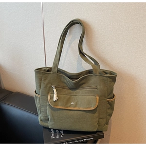 Close-up of dark green corduroy tote bag showing multiple pockets and ribbed texture