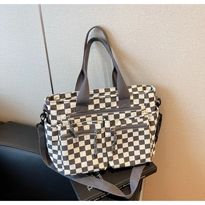Detail of checkered tote bag showing zipper pockets and adjustable shoulder strap