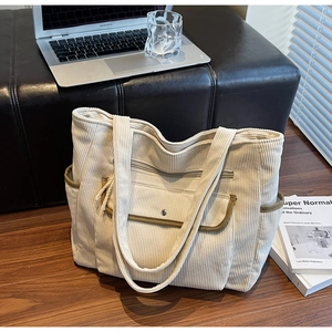 Detail of corduroy tote bag with olive green trim and silver metal snap button pocket
