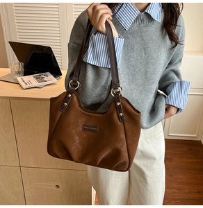 Dettaglio della borsa tote in pelle scamosciata con anelli dorati e base pieghettata