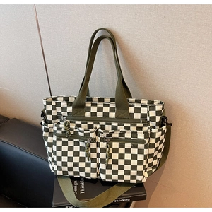 Detail of green checkerboard tote bag with dual front zipper pockets and shoulder strap