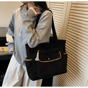 Detail of black corduroy tote with side pocket and beige trimmed zipper front pocket