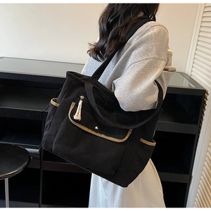 Detail of black corduroy tote bag with contrasting trim, tassels and side pockets