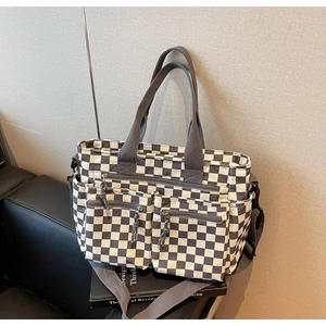 Detail of checkered tote bag showing functional front zipper pockets and canvas texture