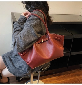 Détail d'un grand sac cabas rouge brique avec cuir à texture litchi et boucle dorée