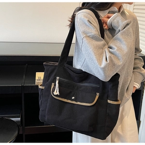 Side view of black corduroy tote bag with multi-pocket design and contrast brown trim