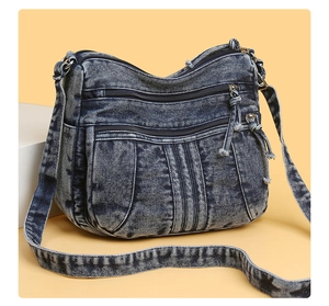 Détail du sac bandoulière en denim bleu délavé avec poches zippées et plis élégants