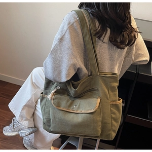 Detail of olive green corduroy tote bag showing metal snap pocket and side compartment