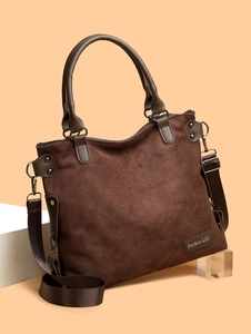Detail of dark brown suede tote bag featuring leather logo tag and textured fabric strap