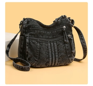 Détail du sac bandoulière en denim gris avec plusieurs zips et texture délavée