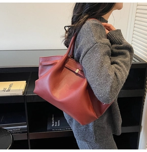 Détail du sac cabas en cuir bordeaux avec boucles argentées porté par un mannequin