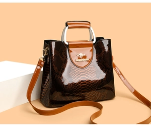 Detailed view of glossy brown snake-pattern faux leather handbag with golden logo