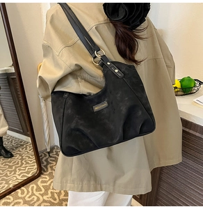 Dettaglio della borsa hobo in pelle scamosciata nera con anelli d'oro e placca logo