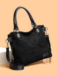 Detail of black suede tote bag with leather trim and silver metal hardware details