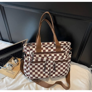 Detail view of checkerboard tote bag with dual front zipper pockets and wide canvas strap