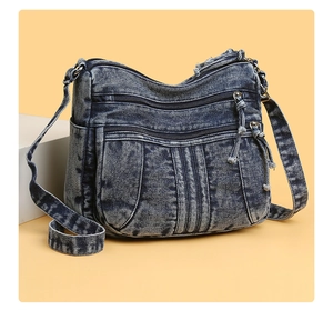 Vue détaillée du sac bandoulière en jean délavé bleu avec plusieurs poches zippées