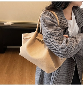 Détail du grand sac cabas beige en cuir grainé porté à l'épaule par un mannequin