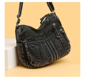 Détail du sac bandoulière en denim lavé avec plusieurs poches zippées et tissu souple
