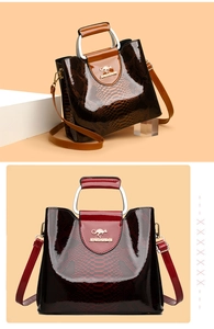 Detail of high-gloss reptile texture handbags with U-shaped metal handles and logo
