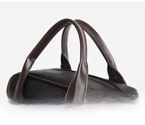 Détail du sac en cuir PU noir à grain litchi avec poignées brunes et fermeture éclair en métal