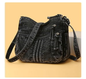 Détail du sac bandoulière en denim noir avec plusieurs poches et compartiments zippés