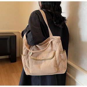 Detailed view of beige corduroy tote bag showing side pockets and flap button pocket