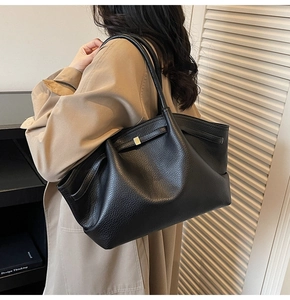Détail du sac cabas noir grainé avec boucle dorée porté par un mannequin en trench
