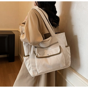 Detail of corduroy tote bag featuring multi-pocket design and olive green trim finish
