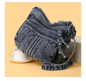 Détail du sac bandoulière en jean montrant trois poches zippées et bords effilochés