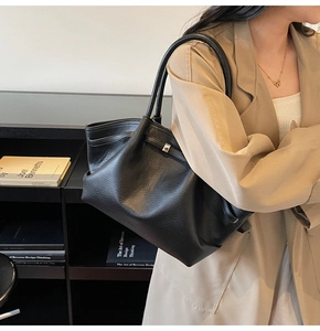 Détail rapproché du sac cabas en cuir noir grainé lychee avec boucle métallique élégante