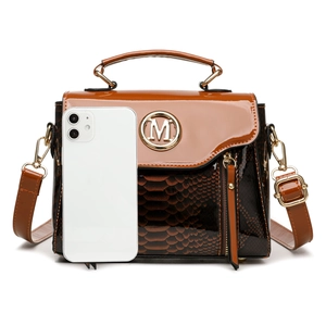 Brown leather crossbody bag with snakeskin texture and M logo shown beside mobile phone