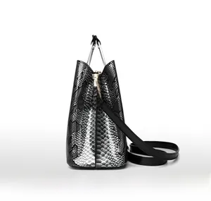 Detail view of black snakeskin barrel handbag featuring silver semicircular metal handles