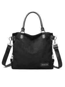 Detail view of large suede tote bag with leather handles and adjustable fabric strap