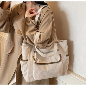 Detail of corduroy tote bag featuring contrast trim and large front pocket with snap button