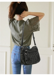 Détail du sac bandoulière en denim noir à poches multiples porté par un mannequin en studio