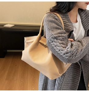 Détail d'un cabas en cuir beige grainé avec fermeture à lanière porté par un mannequin