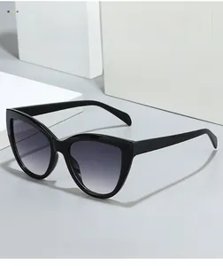 Detail of black cat-eye sunglasses with gradient grey lenses on a white geometric stand