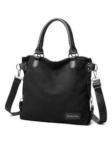Detail of black suede tote bag with leather handles and removable woven strap