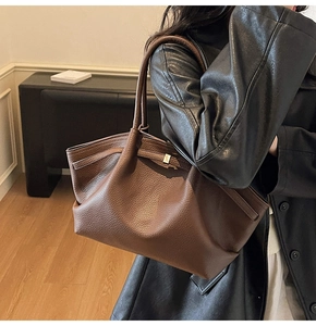 Détail d'un sac cabas en cuir grainé marron foncé porté avec un manteau en cuir