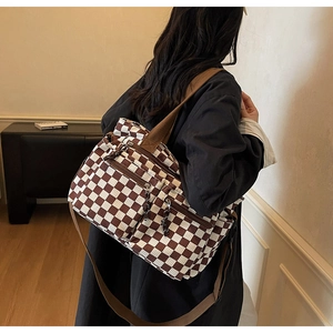 Detail of checkered tote bag with brown zipper pockets and adjustable shoulder strap