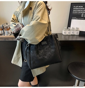 Detail of black large-capacity tote bag in matte finish worn over a shoulder
